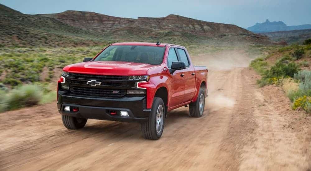 A red 2020 Chevy Silverado 1500 TrailBoss is driving on a dirt road.