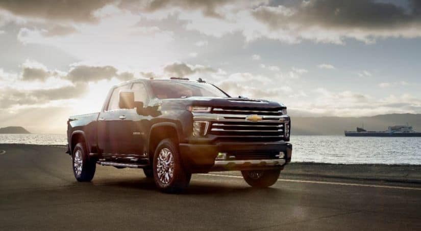 A black 2020 Chevy Silverado 2500HD High Country is parked in front of a river after winning the 2020 Chevy Silverado 2500HD vs 2020 Chevy Silverado 1500 comparison.