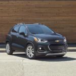 A blue 2020 Chevy Trax is parked in front of a wood wall.