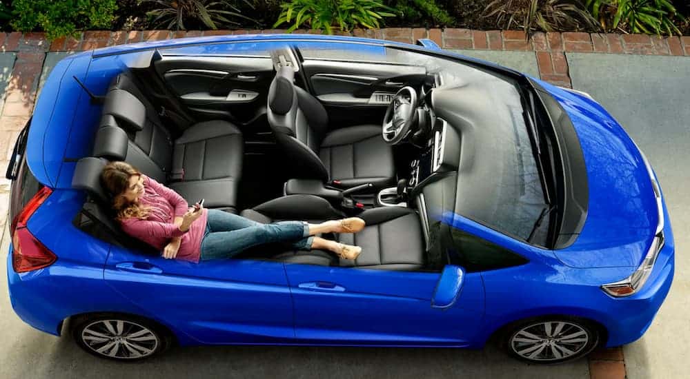 A cut-away view shows a woman using the magic seat in a blue 2020 Honda Fit.