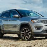 A silver 2020 Jeep Compass is parked on sand in front of grass after winning the 2020 Jeep Compass vs 2020 Ford Escape comparison.
