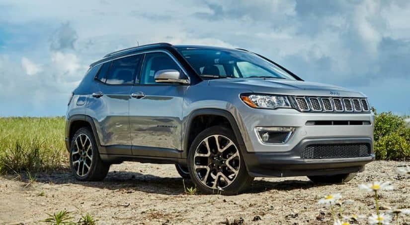 A silver 2020 Jeep Compass is parked on sand in front of grass after winning the 2020 Jeep Compass vs 2020 Ford Escape comparison.