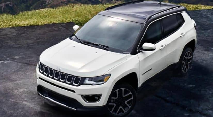 A white 2020 Jeep Compass is parked on pavement in front of grass after winning the 2020 Jeep Compass vs 2020 Nissan Rogue comparison.