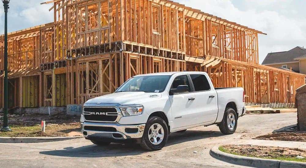 A white 2020 Ram 1500 is at a construction site in front of a wooden frame.