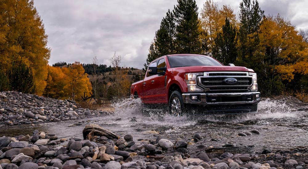 A red 2020 Ford F-250 is driving through a river after losing the 2020 Ram 2500 vs 2020 Ford F-250 comparison.