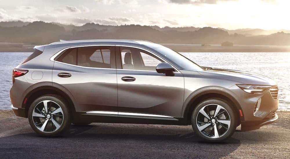 A silver 2021 Buick Envision is shown from the side while parked in front of a river after winning the 2021 Buick Envision vs 2021 Hyundai Santa Fe comparison.