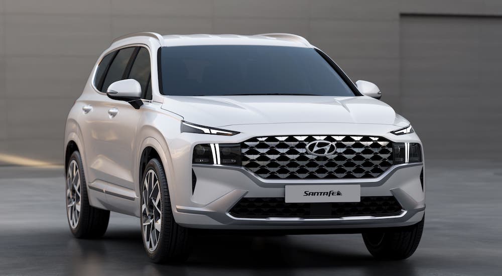A white 2021 Hyundai Santa Fe is parked in front of a gray wall.