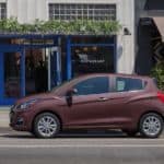 A dark pink 2021 Chevy Spark is parked on a city street.