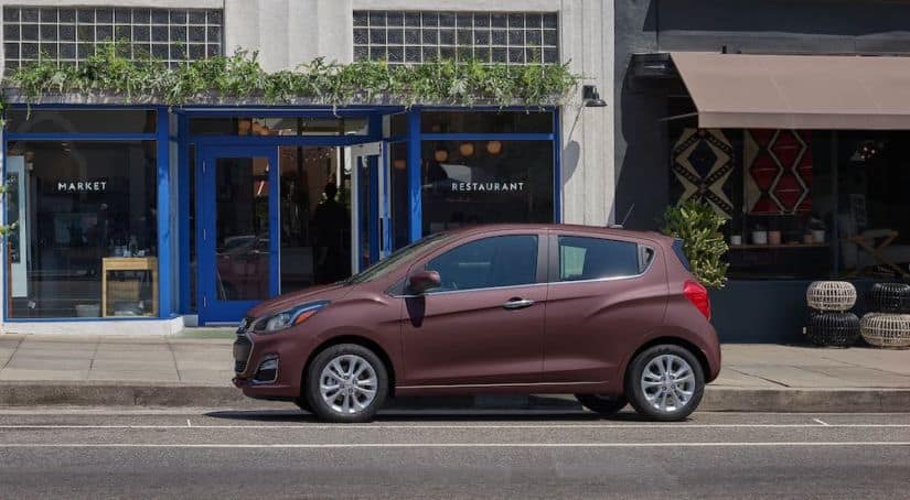 A dark pink 2021 Chevy Spark is parked on a city street.