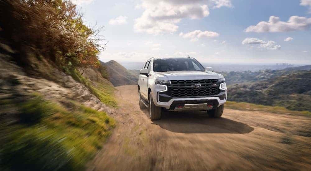 A white 2021 Chevy Tahoe Z71 is driving on a dirt mountain road.