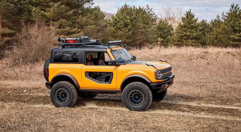 A yellow 2021 Ford Bronco 2-door is driving through a field.