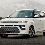 A white 2021 Kia Soul is parked in front of a misty, snow covered mountain.