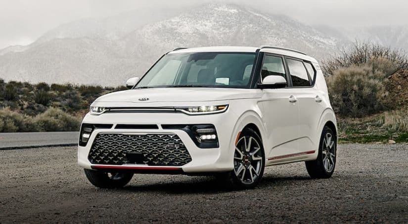 A white 2021 Kia Soul is parked in front of a misty, snow covered mountain.