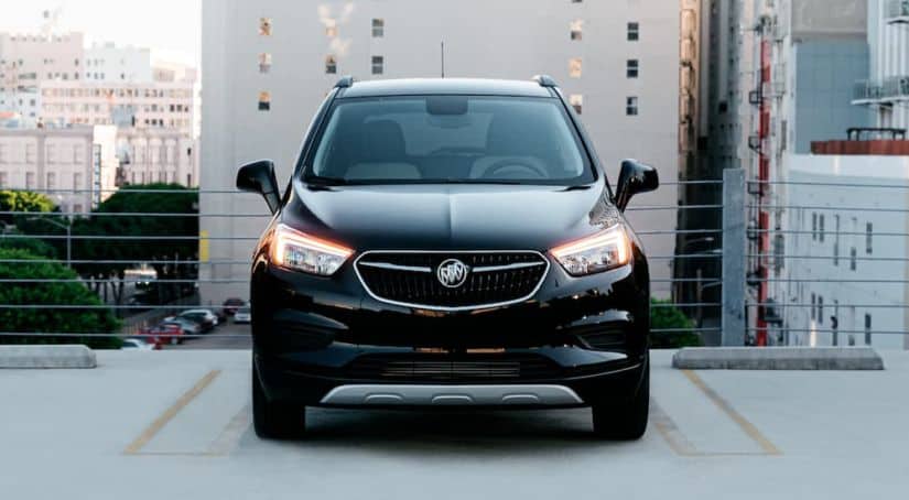 A black 2020 Buick Encore is shown from the front while parked on a parking garage roof deck in a city.
