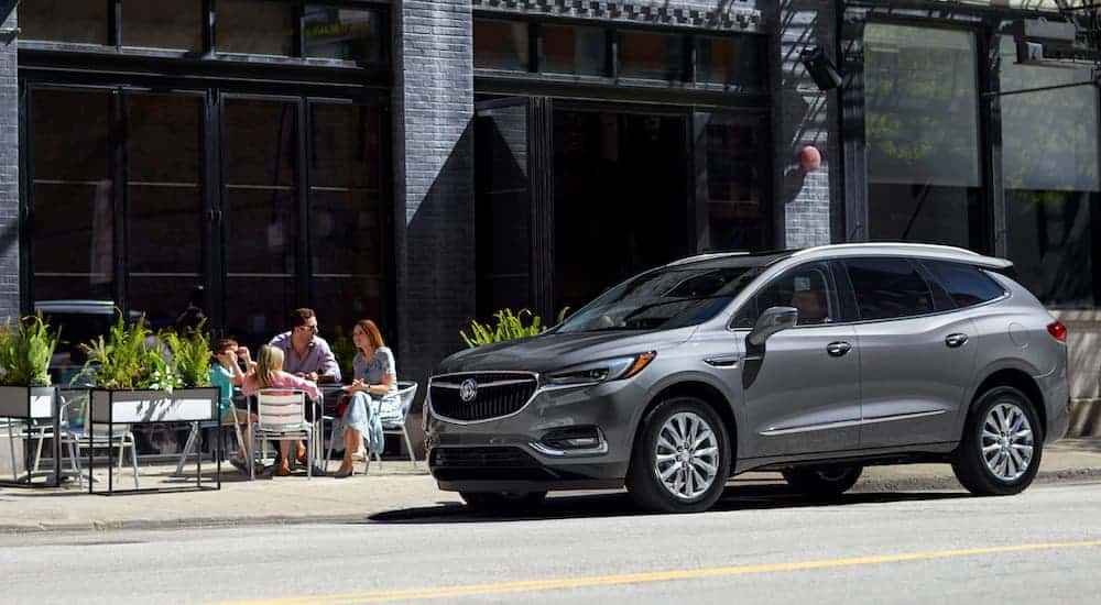 A family is eating outside at a cafe next to a grey 2020 Buick Enclave after leaving the Buick dealer.