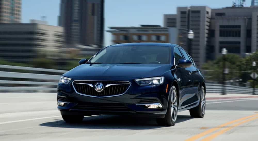 A black 2020 Buick Regal Sportback is driving on a city street.