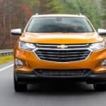A certified pre-owned 2018 Chevy Equinox is shown from the front while driving on a highway.
