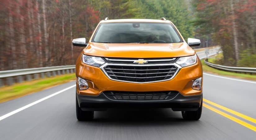 A certified pre-owned 2018 Chevy Equinox is shown from the front while driving on a highway.