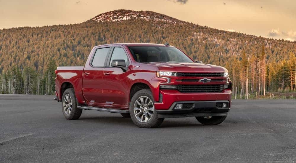 A red 2020 Chevy Silverado is parked in an empty lot in front of a mountain.