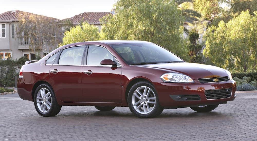 A red 2009 Chevy Impala is parked in front of trees.