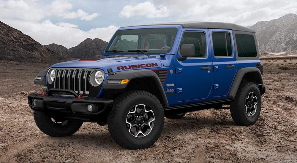 A blue 2020 Jeep Wrangler Unlimited Rubicon Recon is parked off-road in front of mountains.