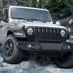 A silver 2020 Jeep Wrangler Unlimited Willys edition is off-roading on rocks after leaving a Jeep dealer near me.