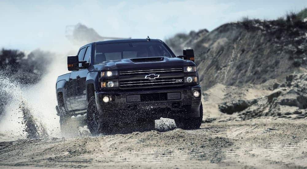 A black 2017 Chevy SilveradoHD Z71 is kicking up dirt on a trail.