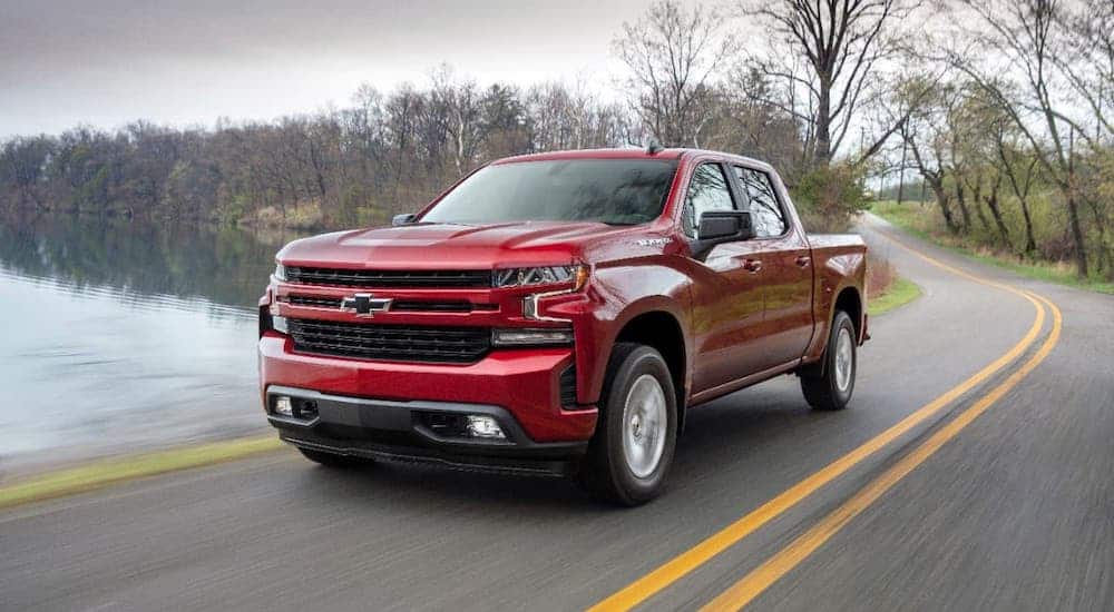 A red 2019 Chevy Silverado 1500 RST is driving next to a pond.