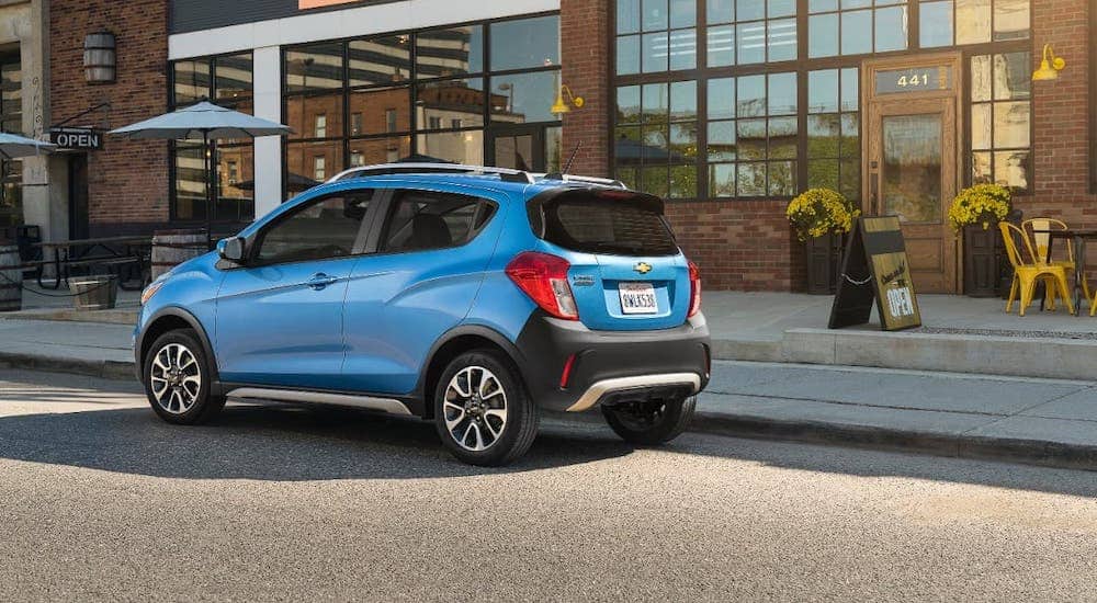 A blue 2017 Chevy Spark is parked in front of a cafe.