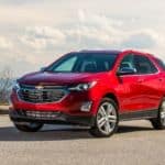 A red 2019 Chevy Equinox is parked on a mountain against a cloudy sky.