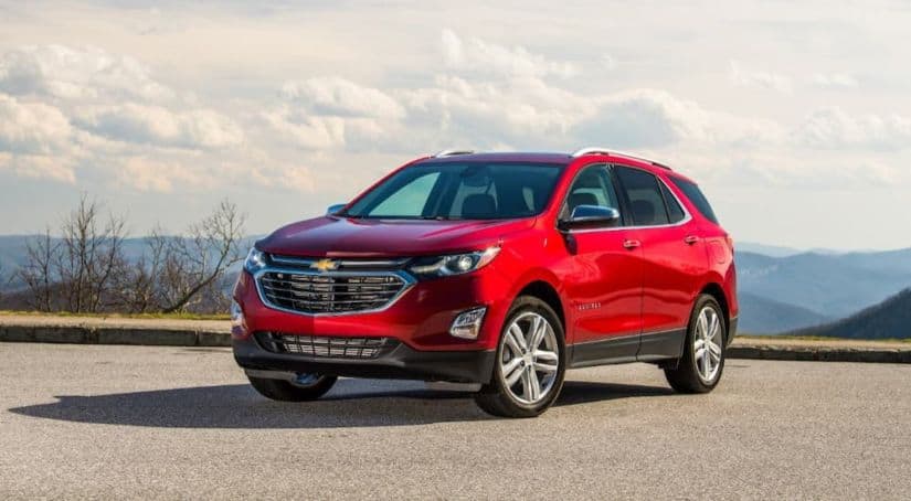 A red 2019 Chevy Equinox is parked on a mountain against a cloudy sky.