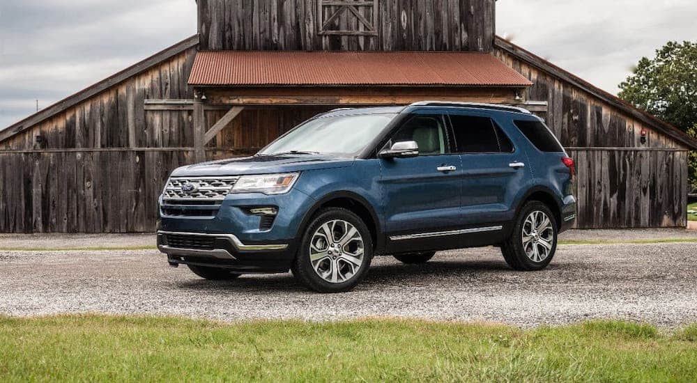 A blue 2019 Ford Explorer is parked in front of a barn.