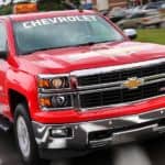 A red rescue themed 2014 Chevrolet Silverado is driving down a paved road.