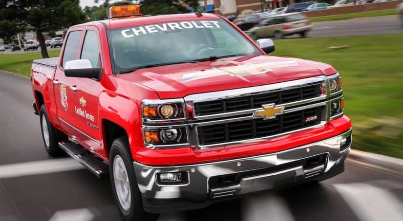 A red rescue themed 2014 Chevrolet Silverado is driving down a paved road.