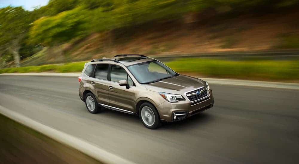 A tan 2017 Subaru Forester Touring, which is popular among used Subarus for sale, is speeding down the road.