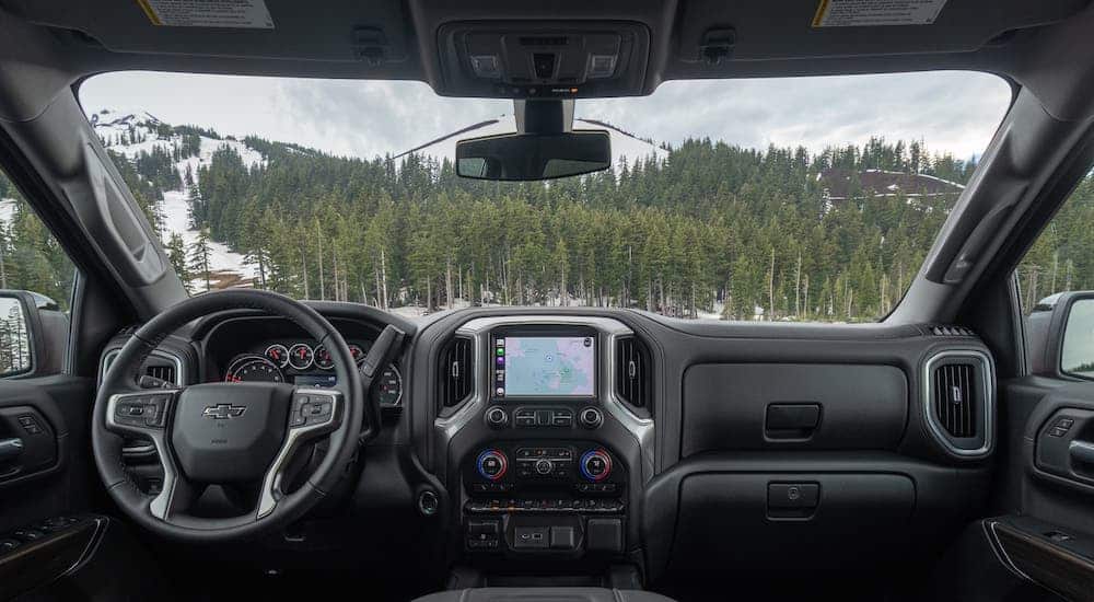 The dashboard of a 2020 Chevrolet Silverado is shown with a view through the windshield overlooking trees and snow.