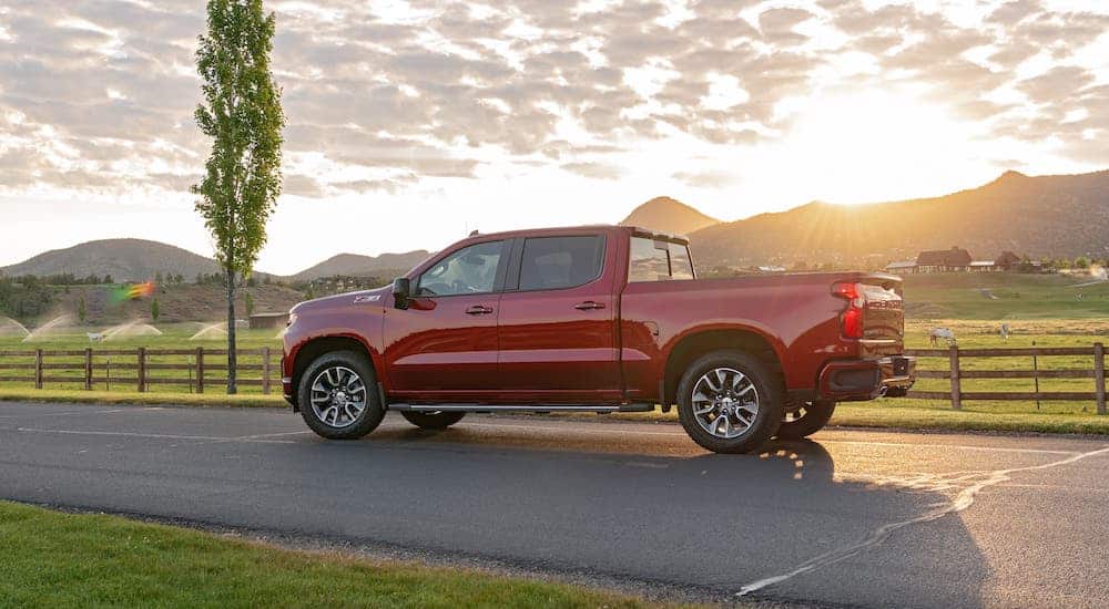 A red 2020 Chevrolet Silverado, shown from the side, is parked in front of a field at sunset.
