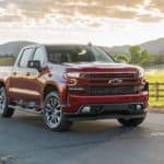 A red 2020 Chevrolet Silverado, which is popular among Chevy Trucks, is parked in front of a field with distant mountains.