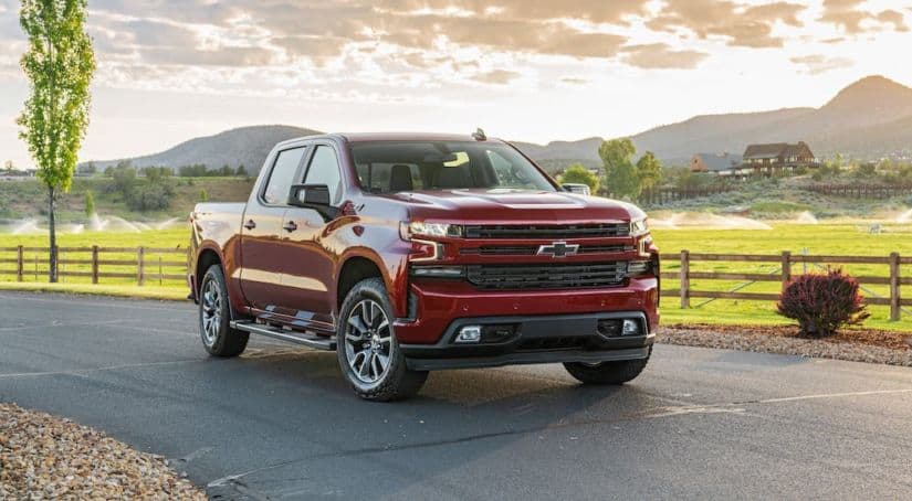 A red 2020 Chevrolet Silverado, which is popular among Chevy Trucks, is parked in front of a field with distant mountains.