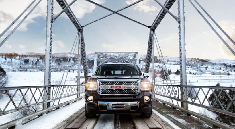 A black 2020 GMC Canyon is shown from the front on a snowy bridge after winning the 2020 GMC Canyon vs 2020 Chevy Colorado comparison.