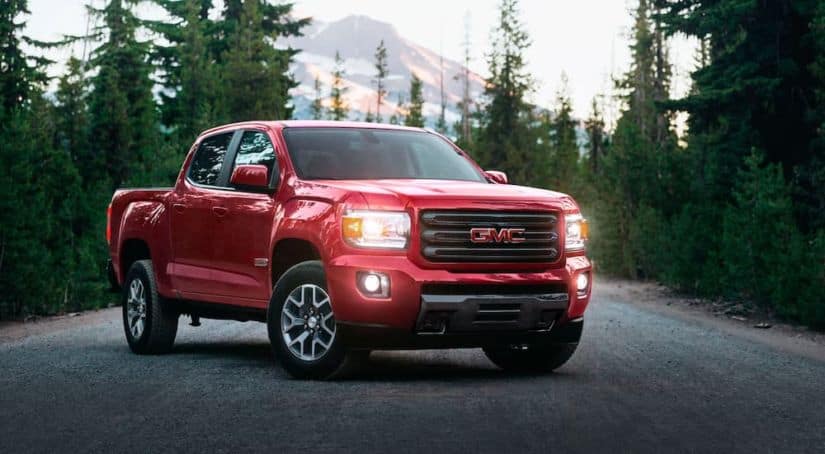 A red 2020 GMC Canyon is parked in front of pine trees and a distant mountain after winning the 2020 GMC Canyon vs 2020 Ford Ranger comparison.