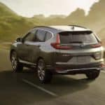A grey 2020 Honda CR-V, which wins when comparing the 2020 Honda CR-V vs 2020 Chevy Equinox, is driving past an ocean inlet.