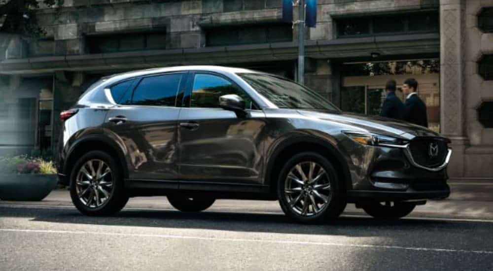 A black 2020 Mazda CX-5 is driving on a city street.