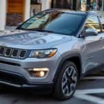 A grey 2020 Jeep Compass is driving on a city street.