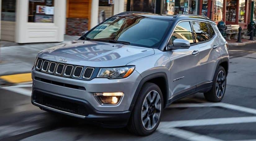 A grey 2020 Jeep Compass is driving on a city street.