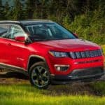A red 2020 Jeep Compass is parked off-road in front of pine trees after winning the 2020 Jeep Compass vs 2020 Mazda CX-5 comparison.