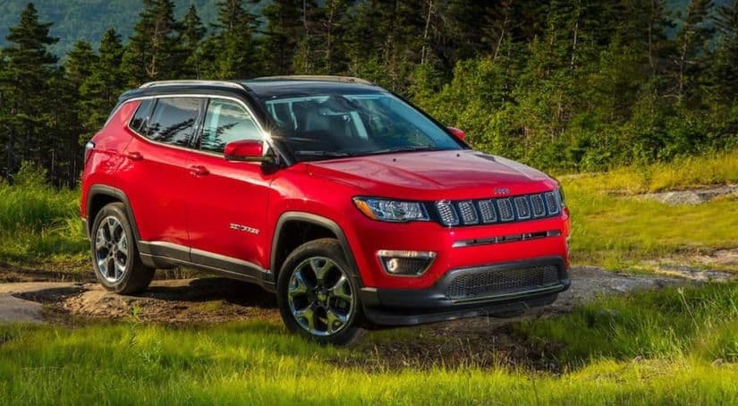 A red 2020 Jeep Compass is parked off-road in front of pine trees after winning the 2020 Jeep Compass vs 2020 Mazda CX-5 comparison.