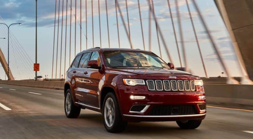 A burgundy 2020 Jeep Grand Cherokee is driving on a cable bridge.