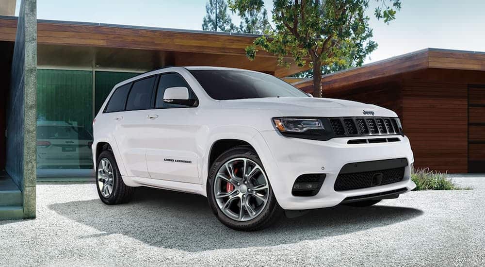 A white 2020 Jeep Grand Cherokee SRT is parked in the driveway of a modern home.