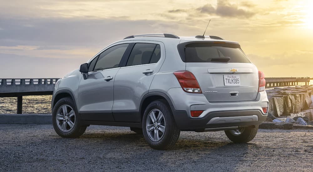 A silver 2021 Chevy Trax is shown from the rear parked in front of a pier.